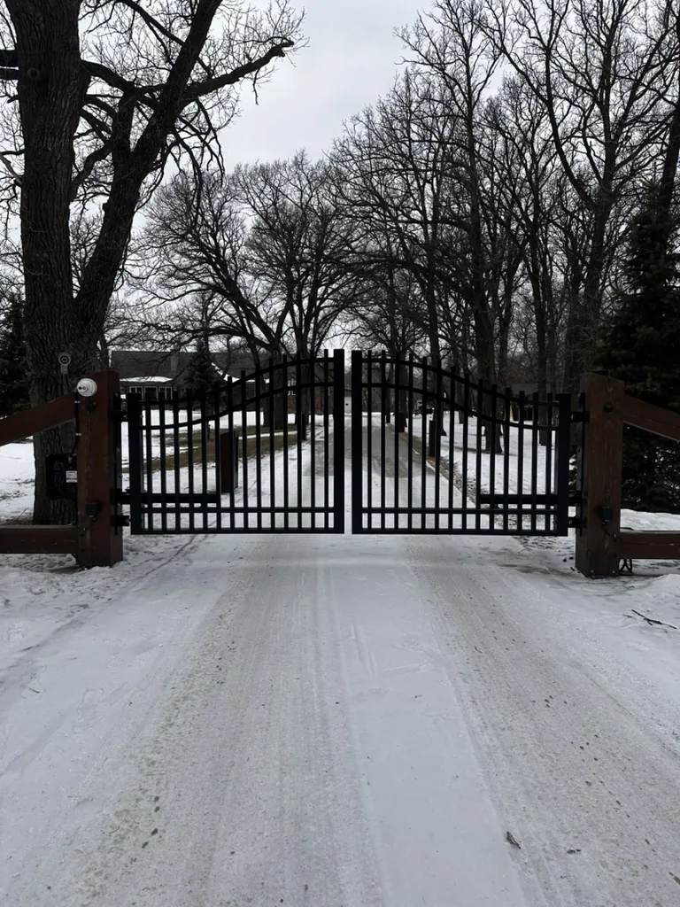 Dual ornamental swing driveway gate on stone pillars